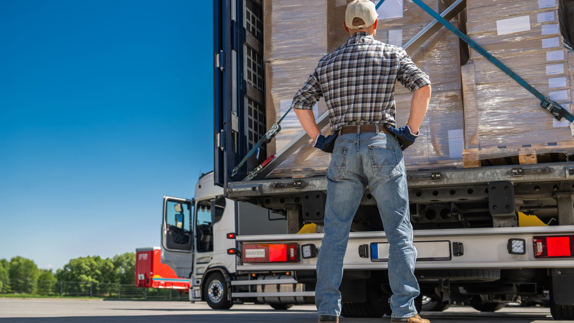 Transporte seguro de carga operador observa su tractocamión cargado con productos bien organizados y sujetos, aprovechando al máximo el espacio.