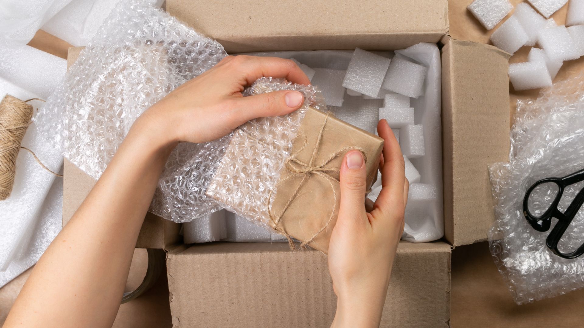 Selección adecuada del embalaje Una persona realiza el empacado de un producto para protegerlo de daños, incluyendo materiales que amorticen el movimiento dentro de la caja.